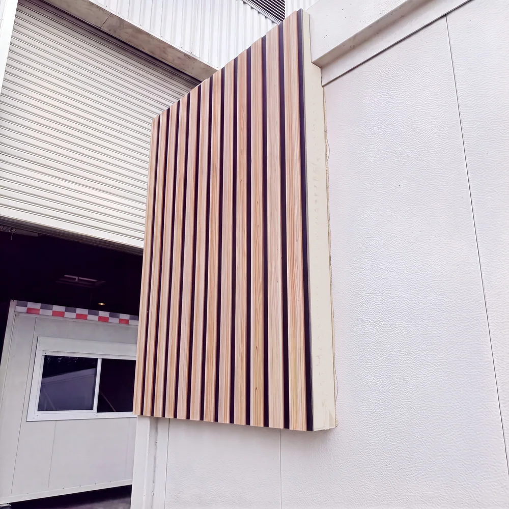 Panneau ModulSkin Panel effet bois à lames verticales, posé en façade sur un module, épaisseur visible sur la tranche